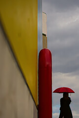 曇り空を見ている赤い傘の女性