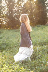 Fototapeta premium Fashion portrait of young hippie woman at sunset posing on nature background