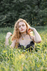 Obraz premium Fashion portrait of young hippie woman at sunset posing on nature background
