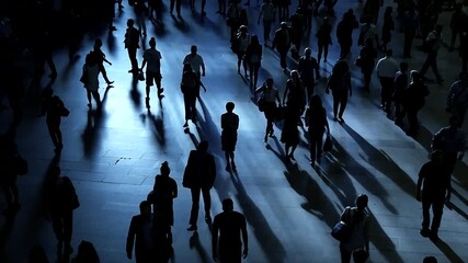 A bustling and crowded urban scene featuring striking shadows as the evening light fades away