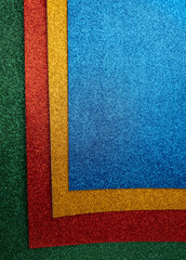 Fototapeta premium Stack of glittery green, red, yellow, and blue textured craft paper sheets