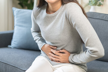 Sick asian young woman in pain, hand holding belly, stomach pain from food poisoning, girl hurt abdomen ache and digestive problem, gastritis or diarrhea. Health care inflammation, abdominal problem