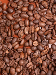 Close-up of roasted coffee beans on brown background for food and beverage concepts