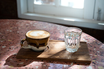 Hot coffee latte with latte art milk foam in cup mug on marble floor desk As breakfast In a coffee shop at the cafe, during business work concept