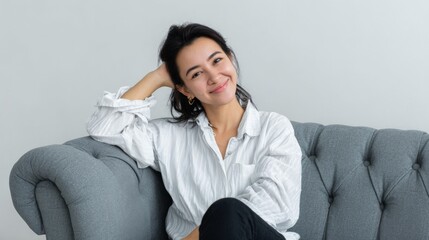 Young asian female relaxing on grey couch in white shirt