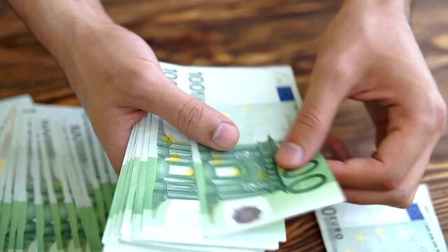 Male hands counting European 100 hundred Euro money banknotes. A man hands counting euro money bills, european economy value. Man converting euro bills manually. Euro currency exchange. - Powered by Adobe