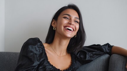 Young hispanic female smiling in black blouse on gray sofa