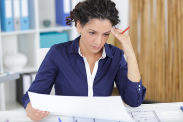 young woman architect constructor analyzing blueprint in office