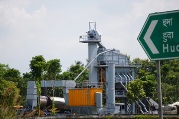 Rice mill silo with green directional sign against clear sky