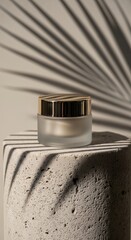Frosted glass cosmetic cream jar with a golden lid on a concrete pedestal, enhanced by a palm leaf shadow, symbolizing natural beauty products.