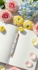 Open blank notebook with a beautiful decorative pen, surrounded by soft pink, yellow, and blue flowers and petals on a clean white background, ideal for journaling or creative concepts.