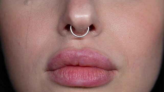 A nose piercing on a beautiful girl.
A nose ring and large lips on a woman's face.
Feminine facial features and beauty.
The face of a young woman with a silver nose ring.