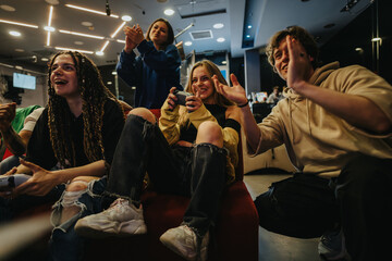 A group of young friends having fun while playing video games in a cozy lounge environment. The...