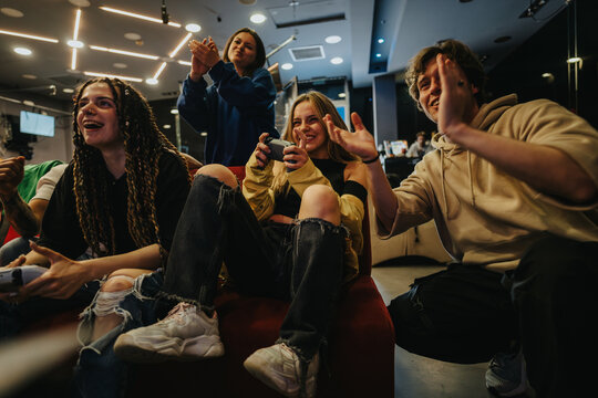 A group of young friends having fun while playing video games in a cozy lounge environment. The atmosphere is filled with joy, connection, and excitement.