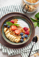 Healthy breakfast bowl with yogurt, granola, fresh berries and banana slices