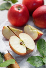 Freshly cut red apples on baking paper with knife and leaves