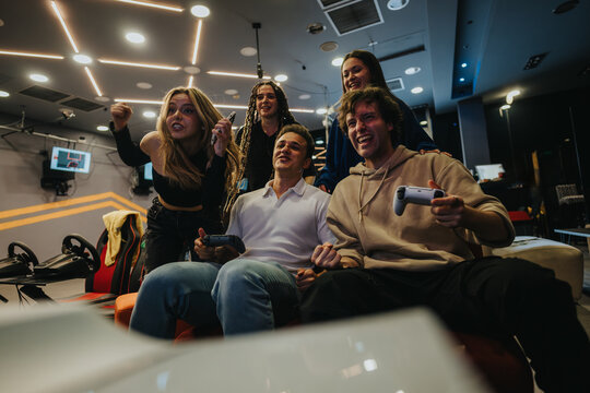 A group of friends having fun playing video games in a dynamic gaming setting, showcasing joy and excitement. - Powered by Adobe