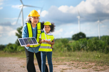 woman and  child are standing in  field holding  solar panel