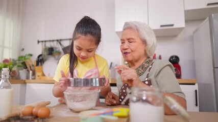 Asian granddaughter baking bakery with grandmother in kitchen at home. 