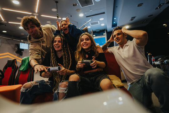 A group of friends enjoys an engaging gaming session while seated in a modern lounge setting, expressing excitement and joy.