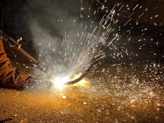 Industrial welding with sparks flying in the dark – high heat, craftsmanship, and metalworking process captured in action.