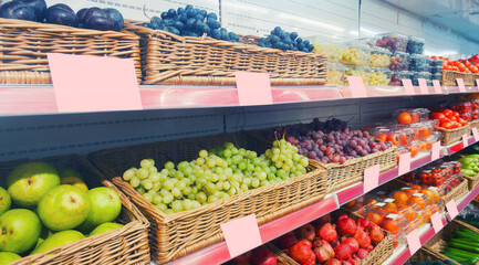 The grocery view with assortment of pears, grapes and other fruits and vegetables.  The showcase with empty blank price tags for copyspace area.