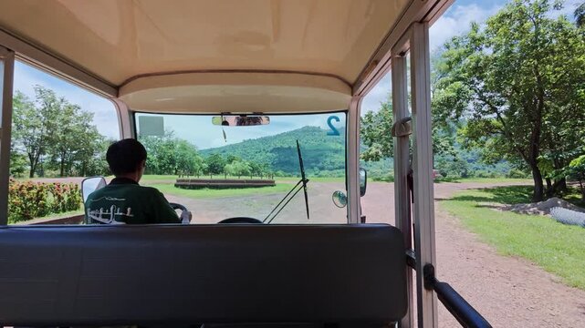 Unrecognizable Park ranger driving an electric golf cart through nature