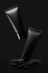 Black plastic cream tube with stone for mockup on black background. Selective Focus.