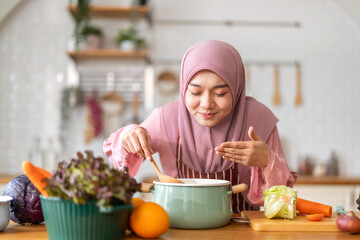 Muslim woman happy cooking healthy meal in kitchen wearing hijab making soup in pot with fresh vegetables food preparation activity nutrition, ramadan healthy recipe preparation, islamic food culture