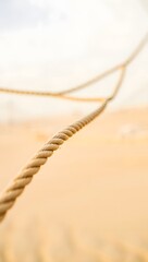 A twisted rope stretches across the frame with a soft beige background blur effect