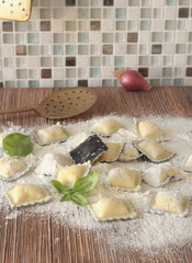 Homemade ravioli with basil leaves on wooden board. Healthy food and organic products.