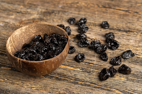 dry prunes made from ripe blue plums in a coconut shell plate, dried plums in a bowl made from natural materials