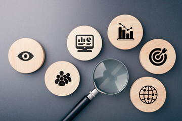 Fototapeta na wymiar A flat lay of magnifying glass and wooden icons representing data analysis, audience targeting, performance metrics, and social media goals for effective content strategy