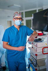 Healthcare professional in blue scrubs manages equipment. A healthcare worker in blue scrubs and a...