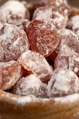 dried kumquat and powdered white sugar in a wooden bowl, dried orange kumquat fruits are placed in a wooden bowl and sprinkled with powdered white beet sugar