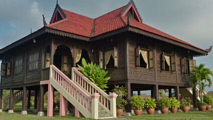 AI Generated: Traditional Malay Wooden House
A hyper-realistic cinematic wide shot of a majestic traditional Malay wooden stilt house with multiple gabled roofs. The house stands elevated on tall stil