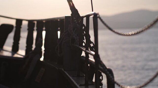 Slow motion close up view from side of vessel. retro style sailing schooner wooden boat boom, lots of ropes, large waves in sunny weather. bow cutting through the water waves at sunset. Travel by sea