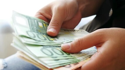 Business man in a suit counting money and holding a lot of euro banknotes in the hands. Business man in a suit counting Euro banknotes and make a payment. A person has lots of cash and is rich. - Powered by Adobe