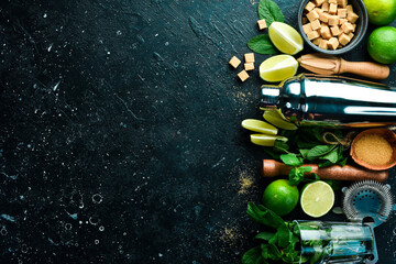 Mojito. Shaker, sugar, fresh lime and mint on wooden board. On a black stone background. Top view.