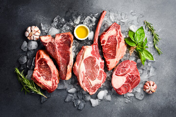 Raw Prime Black Angus steaks for grilling with seasoning: Tomahawk steak, Ribeye, T-bone and Ossobuco steak. Assortment of barbecue steaks.