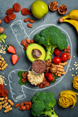A set of fresh fruits, vegetables and nuts laid out in the shape of a stomach. A chalk drawing of a human stomach. The best foods for healthy digestion.
