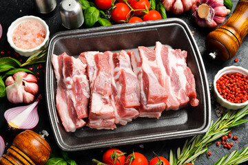 Raw meat. Pork bacon cut into pieces. Meat on a plastic black container from the market. Close-up.