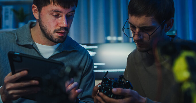 Closeup team adult male engineer collaborate on robotic hand project use AI code solutions machine learn at tech workspace night. Artificial intelligence interface collaboration prototype development.
