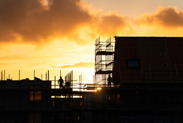 Construction workers working on a housing project in the Netherlands during a tranquil sunrise.


