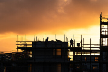Construction workers working on a housing project in the Netherlands during a tranquil sunrise.

