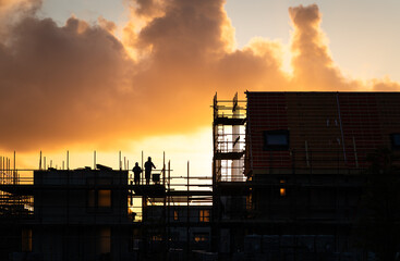 Construction workers working on a housing project in the Netherlands during a tranquil sunrise.

