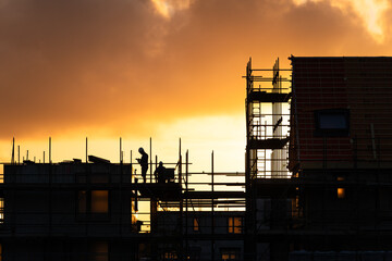 Construction workers working on a housing project in the Netherlands during a tranquil sunrise.

