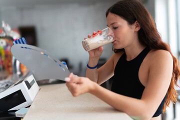 A Young Woman Enjoys a Refreshing Latte Macchiato at a Sunny Bar During a Warm Summer Morning