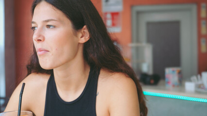 Young Woman Enjoying Refreshing Aperol Spritz Cocktail with Orange Slice and Snacks at a Cozy Bar Table on a Sunny Afternoon