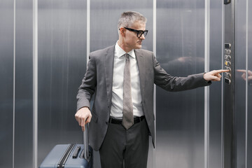 Corporate businessman carrying luggage in the elevator